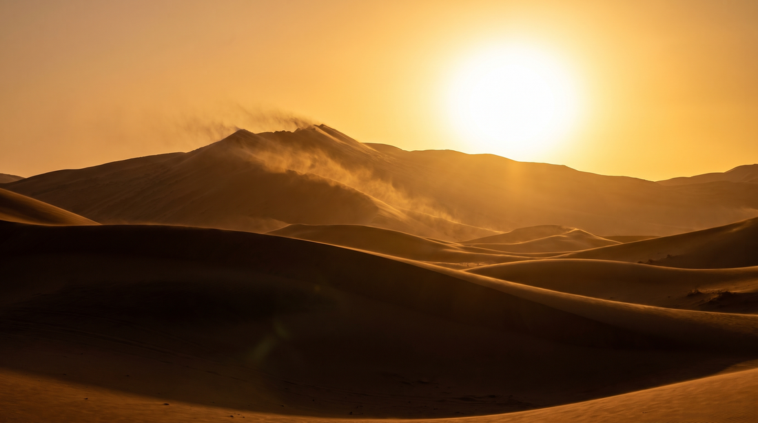 Golden desert dunes with visible heat shimmer at the hottest hour